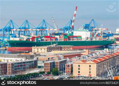 Aerial view of the city and sea cargo port. Large container ship is loaded into the container terminal of Genoa.. Genoa. Cargo port.
