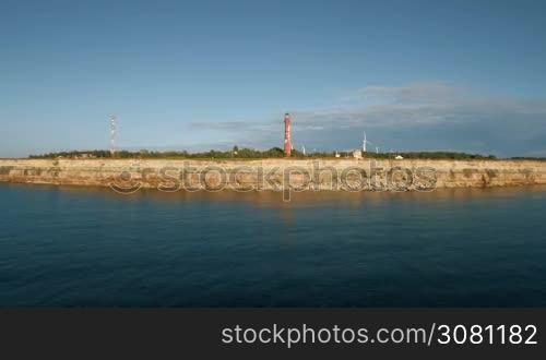Aerial view of the coastline with rocks from the sea and on the land old lighthouse and wind turbines