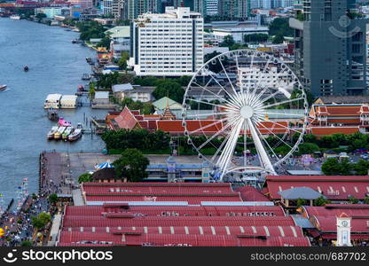 Aerial view of the ferris wheel, Asiatique The Riverfront, near Chao Phraya River with skyscraper buildings in Bangkok Downtown at sunset, urban city, Thailand.