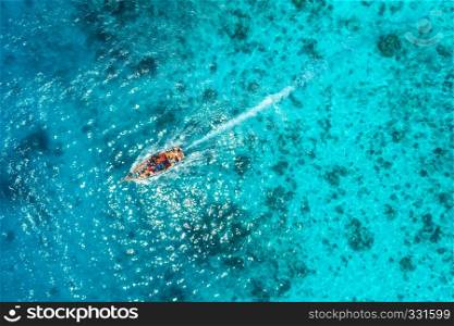 Aerial view of the fishing boat in transparent blue water at sunny day in summer. Top view from drone of floating boat in Indian ocean in Zanzibar, Africa. Landscape with yacht in clear sea. Seascape
