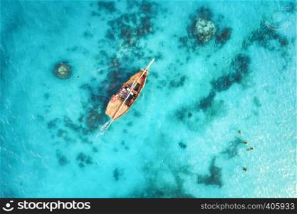Aerial view of the fishing boats in clear blue water at sunset in summer. Top view from drone of boat, sandy beach. Indian ocean. Travel in Zanzibar, Africa. Landscape with sailboats, sea. Seascape