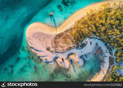 Aerial view of the fishing boats on tropical sea coast with sandy beach and palms at sunset. Fishing village on Indian Ocean, Zanzibar, Africa. Landscape with boat, trees, clear blue water. Top view
