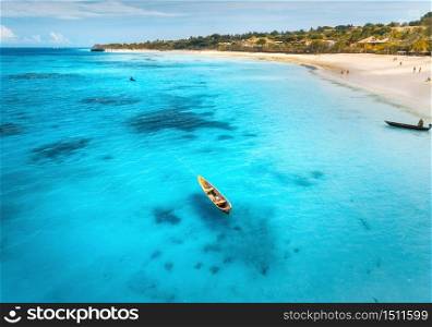 Aerial view of the fishing boats on tropical sea coast with sandy beach at sunrise. Summer holiday in Zanzibar, Africa. Landscape with boat, yacht, clear blue water, green palm trees. Top view. Travel