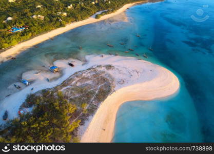 Aerial view of the fishing boats on tropical sea coast with sandy beach at sunset. Summer holiday on Indian Ocean, Zanzibar, Africa. Landscape with boat, green trees, transparent blue water. Top view