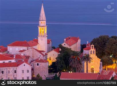 Aerial view of the old city and the bell tower in night illumination. Budva. Montenegro. Budva. Old city at sunset.