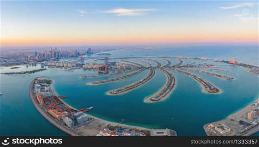 Aerial view of The Palm Jumeirah Island, Dubai Downtown skyline, United Arab Emirates or UAE. Financial district and business area in smart urban city. Skyscraper and high-rise buildings at sunset.