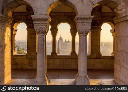 Aerial view of the Parliament of Hungary through Gothic windows of Fisherman&rsquo;s Bastion (Halaszbastya) at sunrise with beautiful sky and clouds , Budapest, Hungary