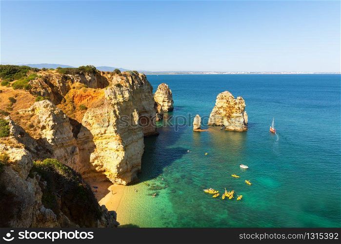 Aerial view of the ship in ocean with rocky cliffs against blue sky, Portugal. Ship in the open ocean