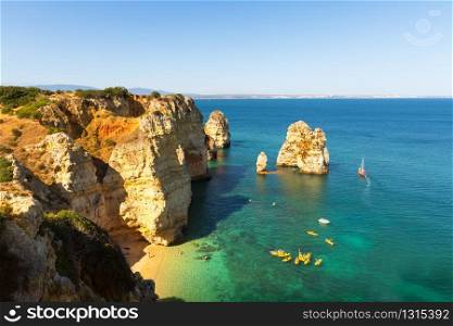 Aerial view of the ship in ocean with rocky cliffs against blue sky, Portugal. Ship in the open ocean