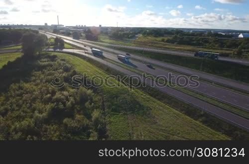 Aerial view of the white vehicle rides on highway through industrial area. Aerial view with background of blue sky and clouds.