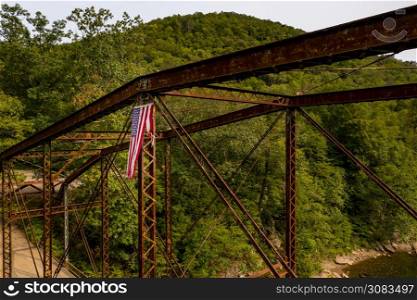 Aerial view of torn damaged Stars and Stripes flag on the historic metal truss Jenkinsburg Bridge near Morgantown. Drone view of torn USA flag on Jenkinsburg Bridge over Cheat River