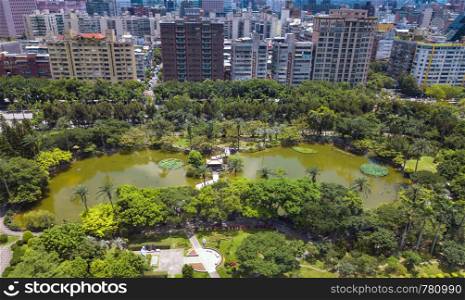 Aerial view of trees in Taipei park garden and reflection of skyscrapers buildings. Green area in smart urban city at noon, Taiwan.