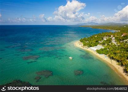 Aerial view of tropical beach with white boat anchored.Samana peninsula,Bahia Principe beach,Dominican Republic.