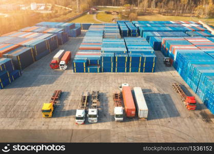 Aerial view of trucks and containers at sunset. Top view of autotrucks, container warehouse in logistics terminal for export and import. Business. Freight transportation. Shipping and cargo. Industry