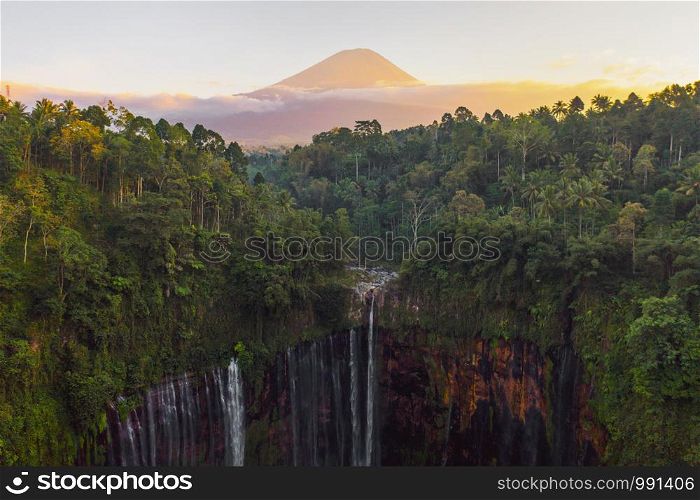 Aerial view of Tumpak Sewu waterfall and Semeru mountain at sunrise located in east java, Lumajang, Indonesia. Natural landscape background.