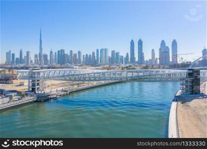 Aerial view of twisted Bridge. Structure of architecture with lake or river, Dubai Downtown skyline, United Arab Emirates or UAE. Financial district and business area in urban city with blue sky.
