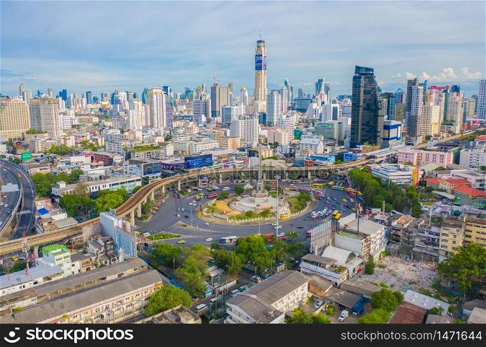 Aerial view of Victory Monument on busy street road. Roundabout in Bangkok Downtown Skyline. Thailand. Financial district center in smart urban city. Skyscrapers at sunset.
