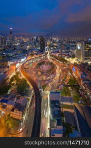 Aerial view of Victory Monument with car light trails on busy street road. Roundabout in Bangkok Downtown Skyline. Thailand. Financial district center in smart urban city. Skyscrapers at night.