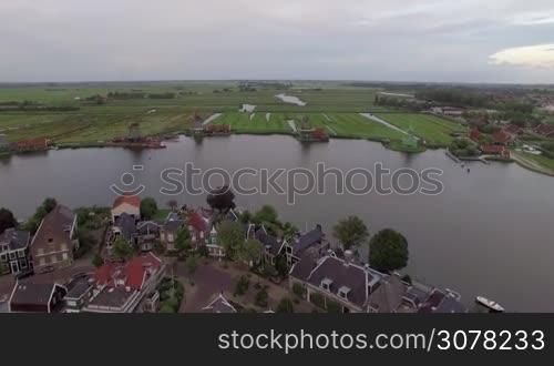 Aerial view of waterside village, old windmills and green fields in Netherlands