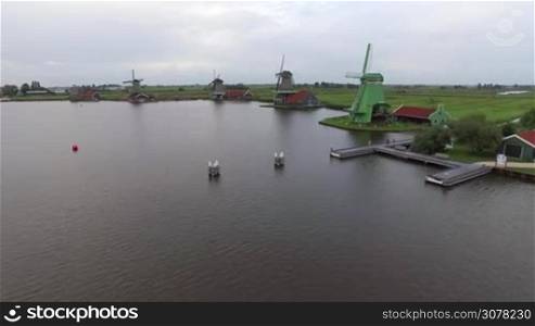 Aerial view of waterside windmills and scene with green fields in Netherlands