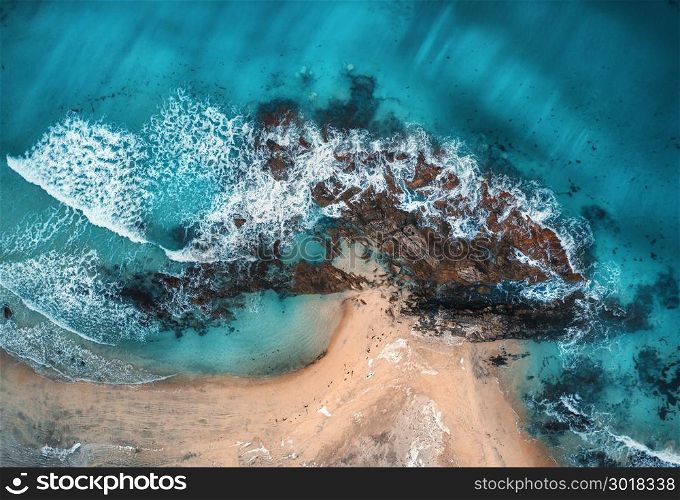Aerial view of waves, rocks and transparent sea. Summer seascape with ocean, sandy beach, beautiful waves, cliffs, blue water at sunset. Top view from drone. Rocky coastline. Travel. Maldives. Concept