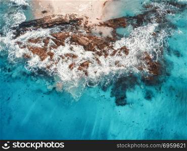 Aerial view of waves, rocks and transparent sea. Aerial view of waves, rocks and transparent sea. Summer seascape with ocean, sandy beach, beautiful waves, cliffs, blue water at sunset. Top view from drone. Rocky coastline. Travel. Maldives. Concept. Aerial view of waves, rocks and transparent sea