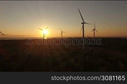 Aerial view of wind generators in the evening sky on the field. Wind generators rotate blades and extract electricity