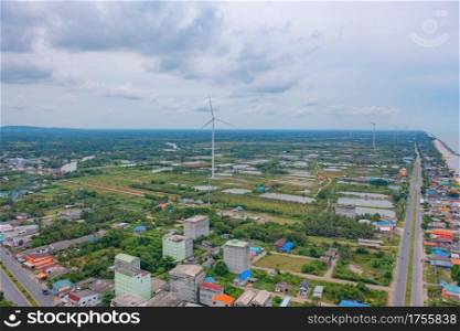 Aerial view of wind turbine with residential buildings in Nakhon Si Thammarat with sea skyline, Thailand. Urban town city in Asia. Architecture landscape background.