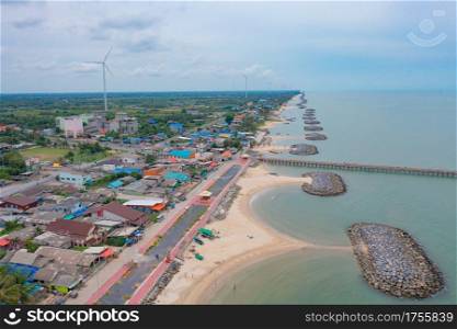 Aerial view of wind turbine with residential buildings in Nakhon Si Thammarat with sea skyline, Thailand. Urban town city in Asia. Architecture landscape background.