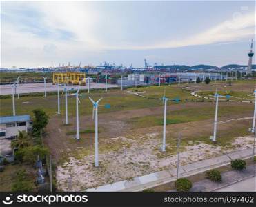 Aerial view of wind turbines and container cargo ship in the export and import business and logistics international goods in urban city in Laem Chabang, Chon Buri, Thailand. Power and energy concept.
