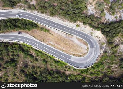 Aerial view of winding road in high mountain pass trough green pine woods. High quality photo. Aerial view of winding road in high mountain pass trough green pine woods.
