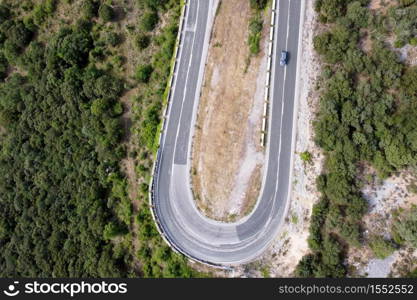 Aerial view of winding road in high mountain pass trough green pine woods. High quality photo. Aerial view of winding road in high mountain pass trough green pine woods.