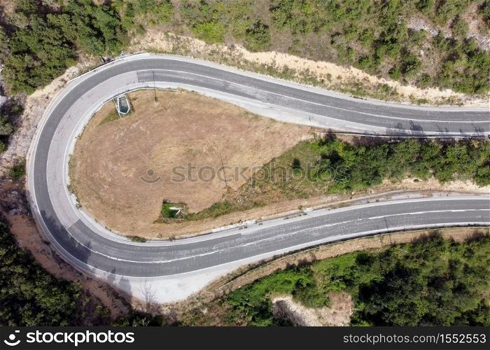 Aerial view of winding road in high mountain pass trough green pine woods. High quality photo. Aerial view of winding road in high mountain pass trough green pine woods.