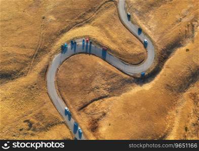 Aerial view of winding road in mountain pass at sunset in golden autumn. Passo Giau, Dolomites, Italy. Beautiful curving roadway, cars, orange grass, alpine meadows. Landscape with highway in fall