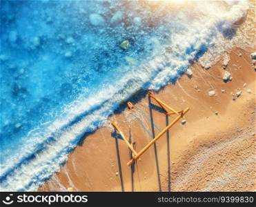 Aerial view of young woman on the swing, beautiful blue sea with waves, sandy beach at sunset. Summer holiday in Oludeniz, Turkey. Top view of girl on the wooden swing, sea coast, clear water. Travel