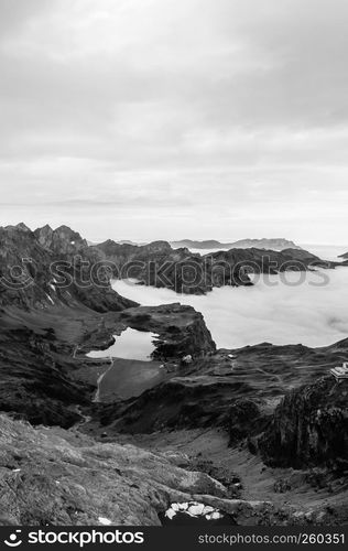 Aerial view over cloud, high grass land rocky alpine mountain valley and lake Trubsee of Titlis in Engelberg, Switzerland