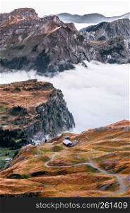 Aerial view over cloud, high grass land rocky alpine mountain valley of Titlis in Engelberg, Switzerland