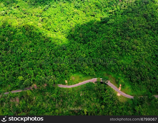 Aerial view over mountain road going through forest landscape