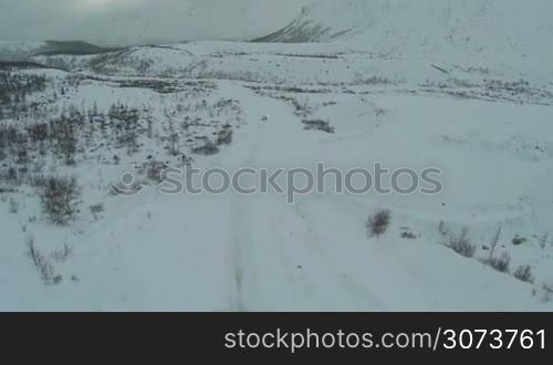 Aerial view over snowy hills and alone car on the road