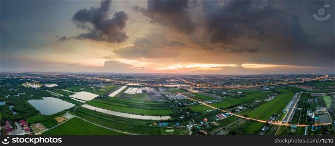 Aerial view panorama of sunset over paddy fields and highway in suburban of Bangkok, Thailand
