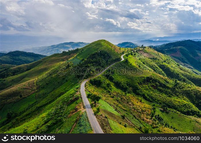 aerial view road way on the green mountain peak in the rain season in morning mist and blue sky background at chiang rai thailand