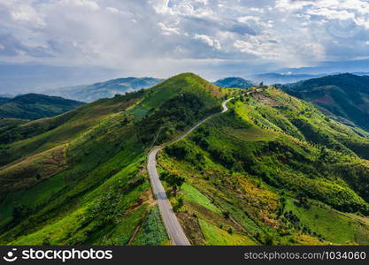 aerial view road way on the green mountain peak in the rain season in morning mist and blue sky background at chiang rai thailand