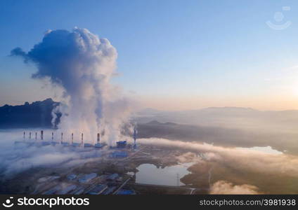 Aerial view steam fumes above the coal power plant in large area The machine is working to generate electricity the morning with fog and clouds.. Aerial view of coal-fired power plants.