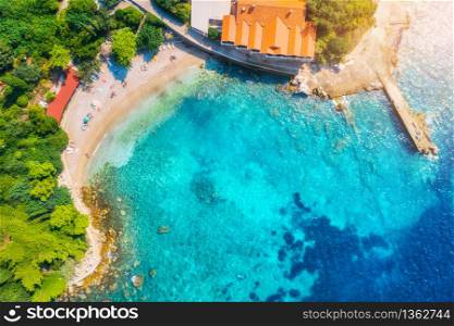 Aerial view with beautiful sea coast, sandy beach, clear blue water, hotels and green trees at sunset. Summer tropical landscape. Top view of blue sea, buildings, rocks and forest. Luxury resort