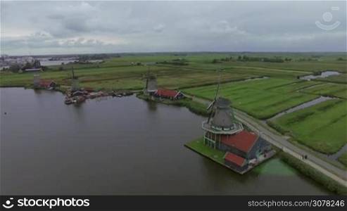 Aerial - Village in Netherlands with view to riverside old windmills and vast green fields