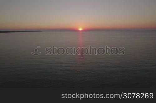 Aerial waterscape. Quiet sea with pier and distant coast at sunset. Thessaloniki, Greece