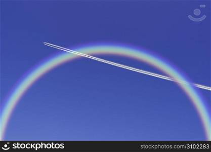 Aeroplane high in the sky with the gliding through a rainbow