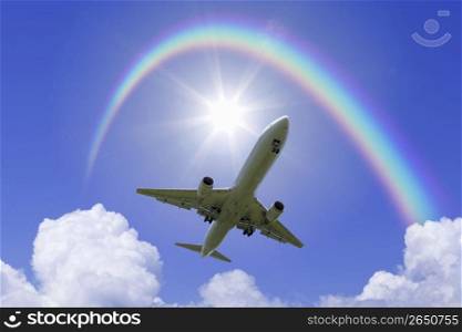 Aeroplane high in the sky with the sun shining brightly through a rainbow