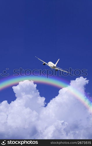 Aeroplane high in the sky with the sun shining brightly through a rainbow