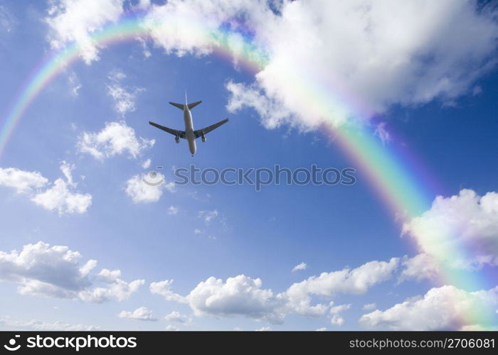 Aeroplane high in the sky with the sun shining brightly through a rainbow